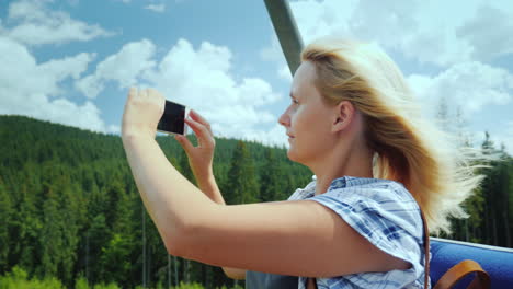 a middle-aged woman takes pictures of beautiful landscapes sits on a bench of a ski lift holidays in