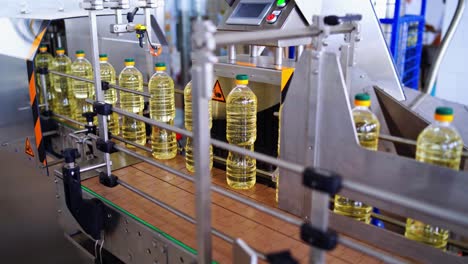 modern factory of food oil production. row of full plastic bottles of oil on a conveyor line. fresh sunflower oil inside the automated manufacture.