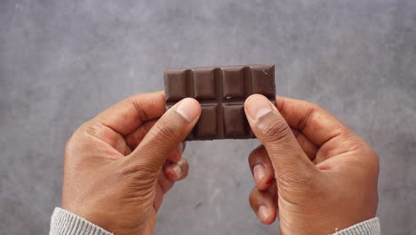 close up of hands breaking a chocolate bar