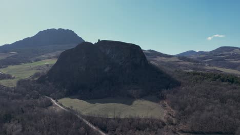 Aerial-footage-of-Pietra-Perduca,-volcanic-rock,-church-set-at-top-stone-immersed-in-countryside-landscape,-cultivated-land-in-Val-Trebbia-Bobbio,-Emilia-Romagna,-Italy