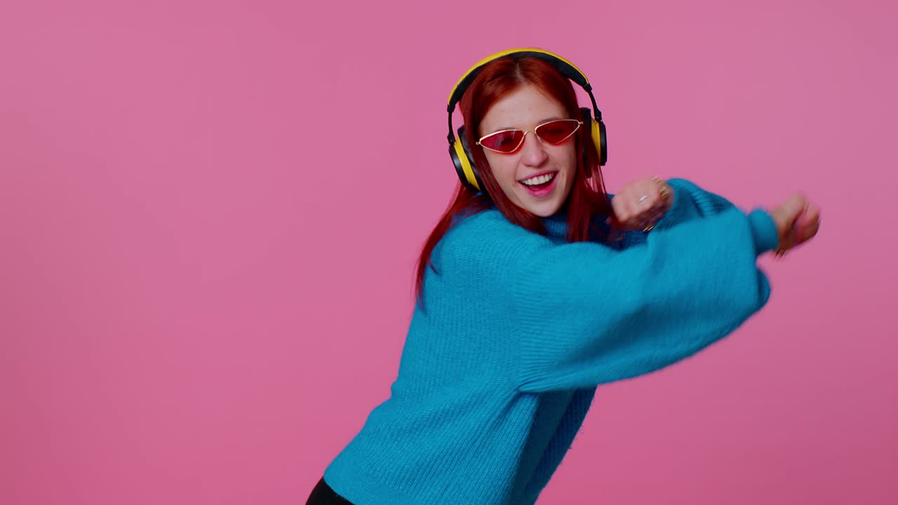 Cheerful attractive girl listening music via headphones and dancing disco fooling around having fun