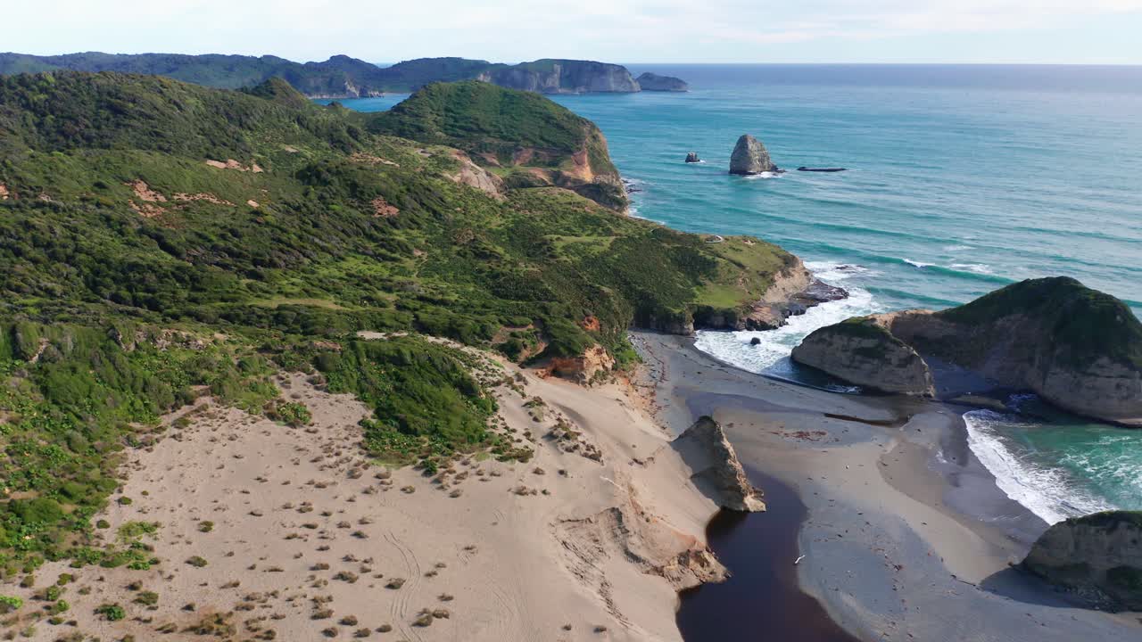 vuelo aéreo sobre la playa hacia la costa verde con olas rompiendo suavemente en la isla de chiloé, chile
