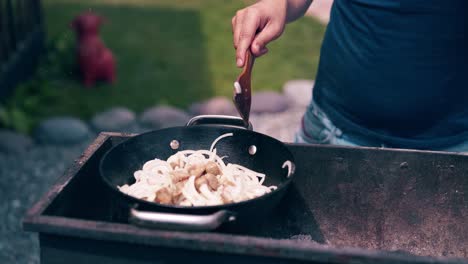 Close-up-Young-man-makes-pilaf-in-a-cauldron-on-a-grill-on-an-open-fire