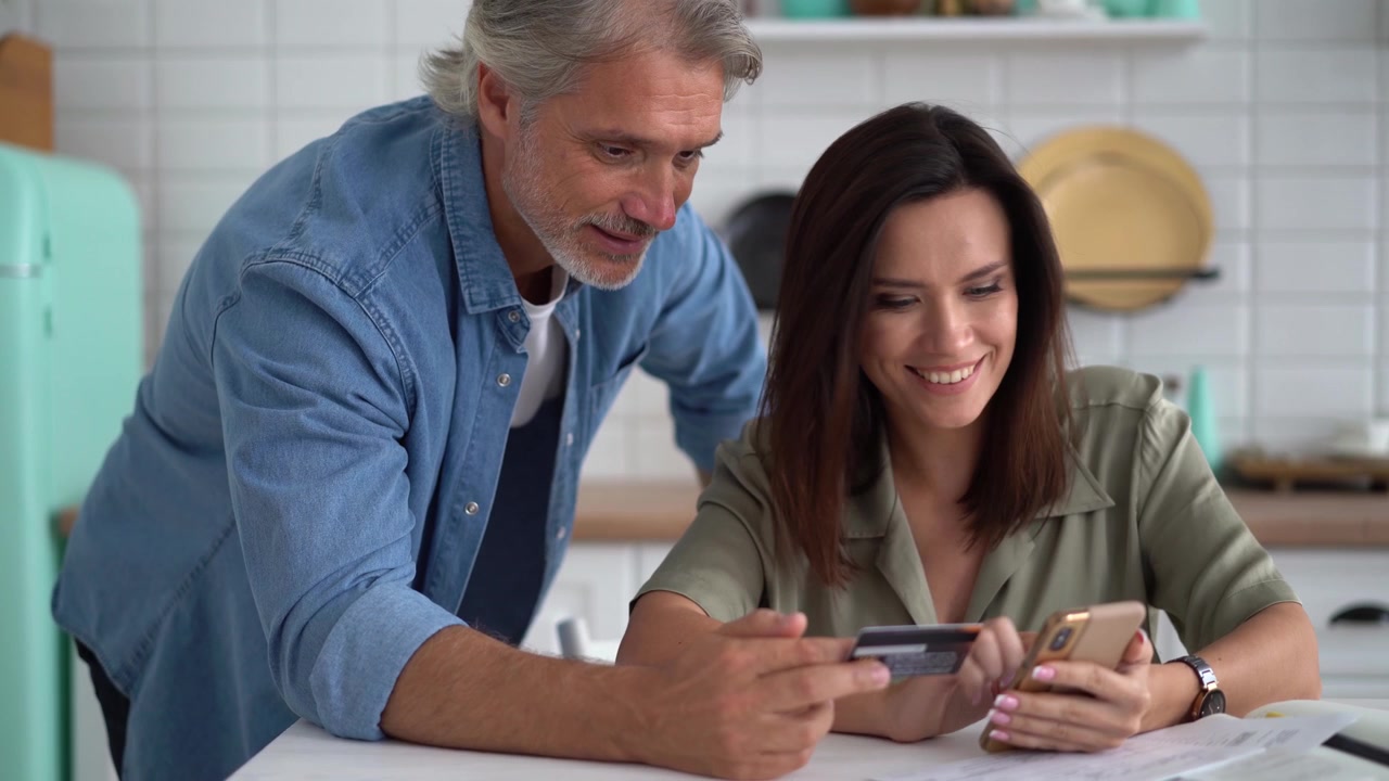 Pareja comprando en línea juntos usando un teléfono inteligente y una tarjeta de crédito.