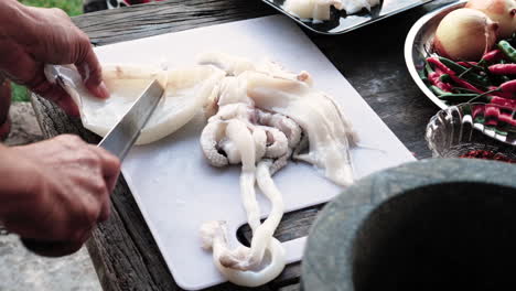 Handheld-Shot-Chef-Schneidet-Frischen-Tintenfischkörper-Auf-Holztisch-Im-Freien