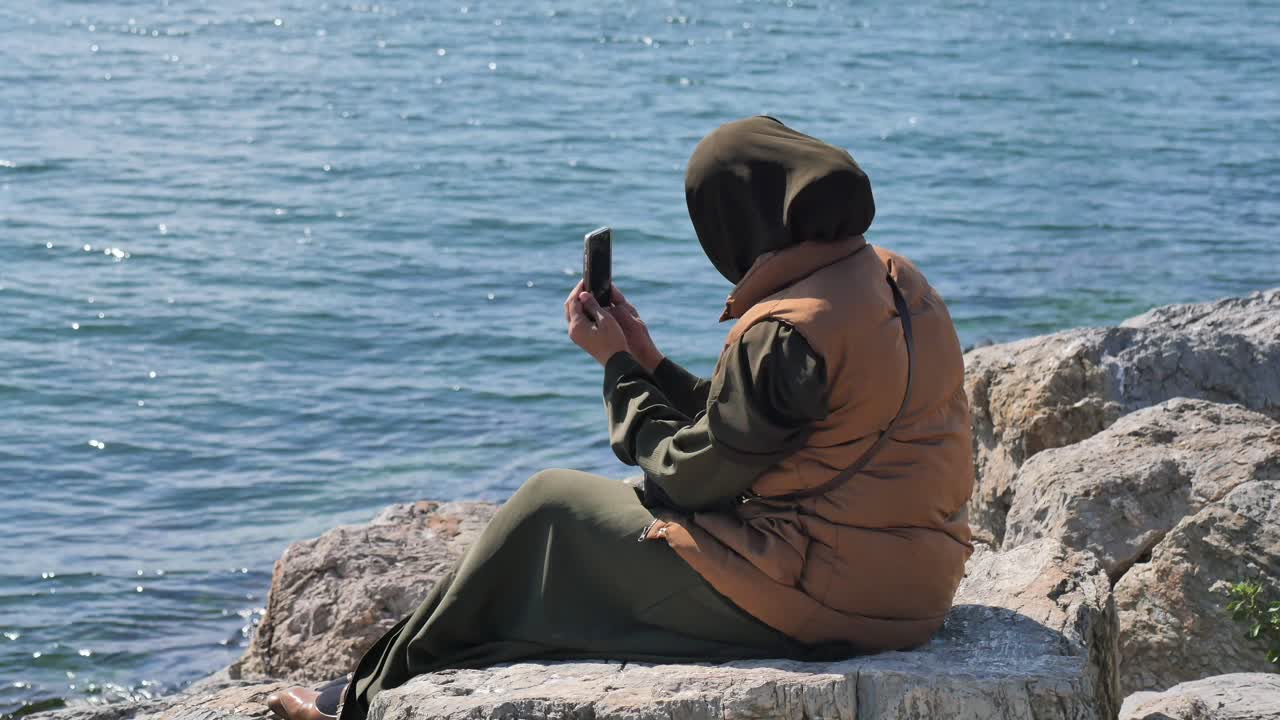 Kvinde bruger telefon ved havet