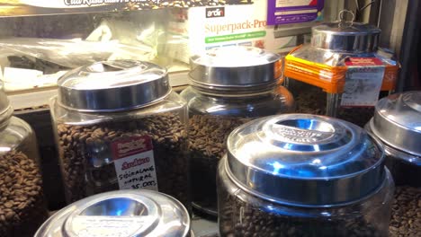 several roasted coffee variants are placed in glass jars sold by retail coffee traders at a traditional market.