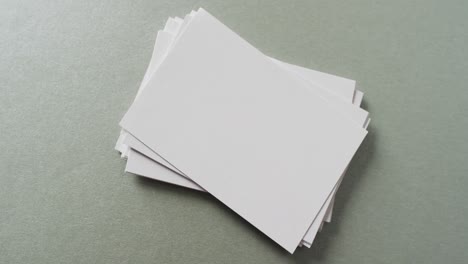 Multiple-blank-white-business-cards-on-green-background,-copy-space,-slow-motion