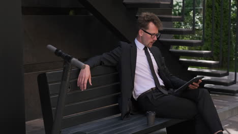 businessman relaxing outdoors with tablet