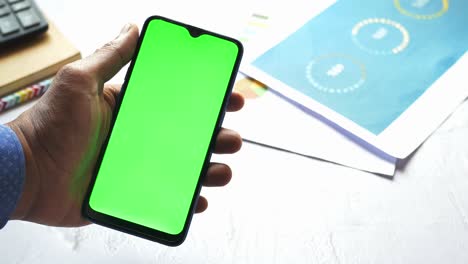 man holding smartphone with green screen mockup - business and finance concept