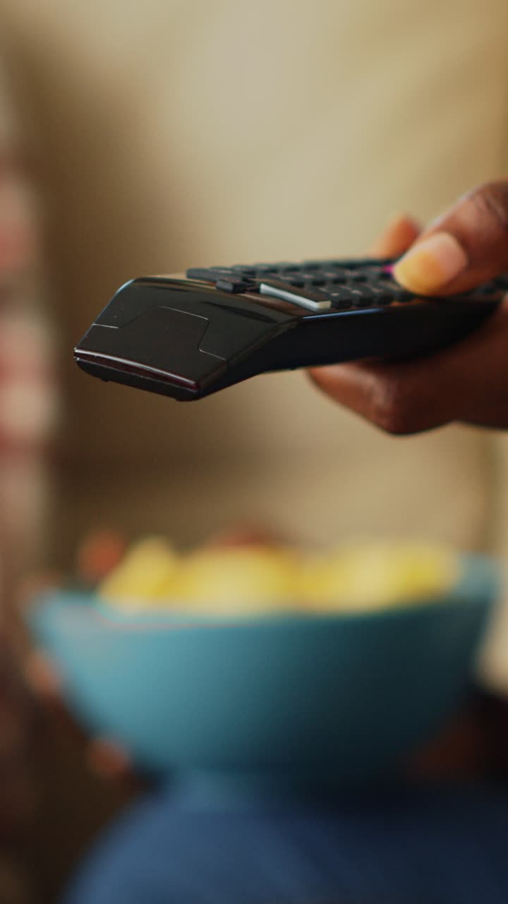 Video verticale: donna che cambia canale con il telecomando della TV