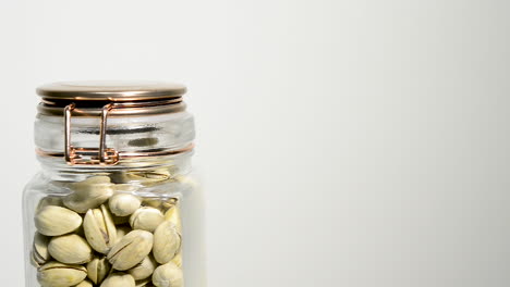 A-sealed-jar-of-pistachio-nuts-rotating-counterclockwise-on-a-white-background