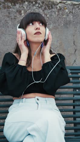 woman sitting in the city bench outdoor and relaxing with music