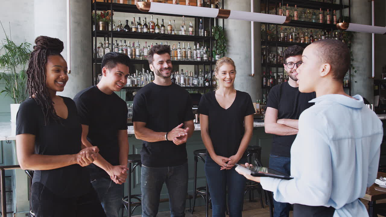 gerente de restaurante femenino con tableta digital dando al equipo hablar con el personal de espera