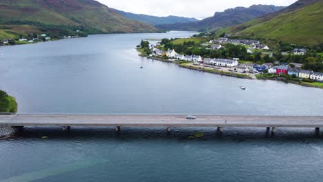 Autos-Que-Conducen-Sobre-El-Puente-Cerca-Del-Castillo-De-Eilean-Donan-En-Dornie,-Costa-Oeste-De-Escocia,-Tierras-Altas-Escocesas---Imágenes-De-Drones-Aéreos-4k-Hd-Vuelan-A-La-Derecha