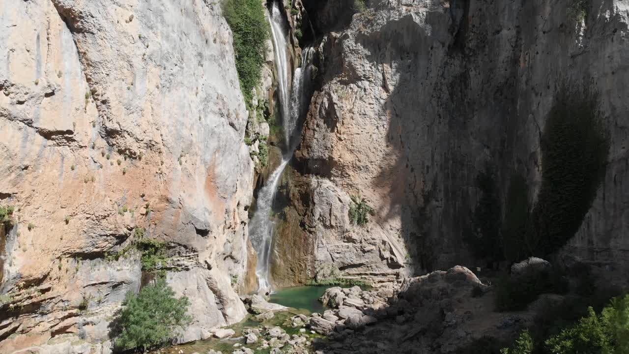 disparo ascendente a la cascada de remordimiento en las montañas, mientras el agua cae desde las alturas, tallando un estanque en piedra como formando el entorno