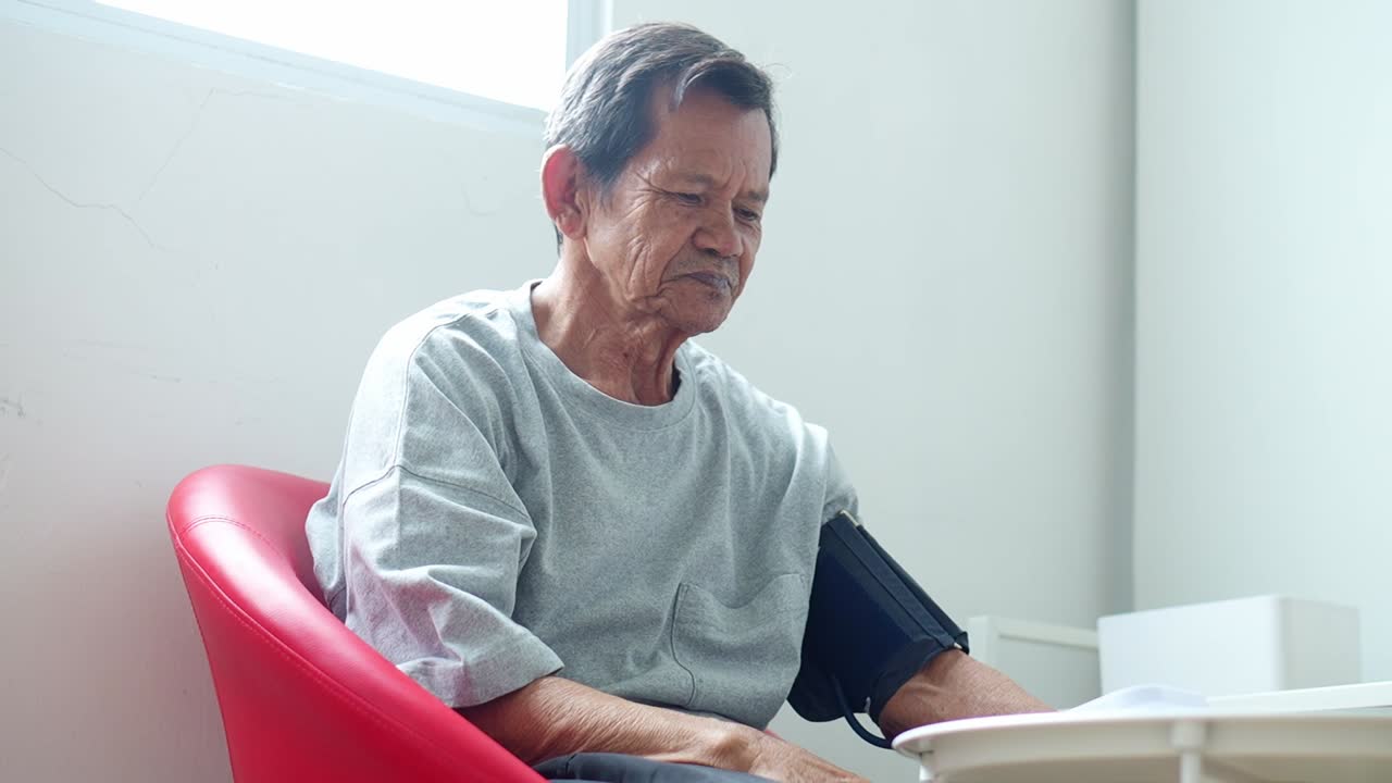 Elderly asian man felling calm while checks blood pressure at home