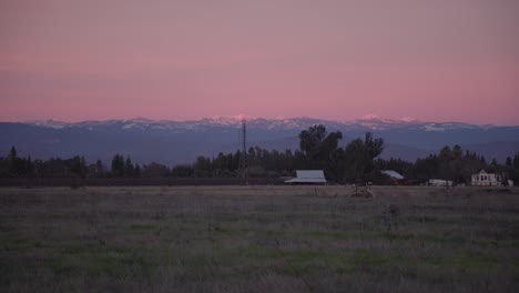 a pastel sky over the sierra nevada mountains with power lines and a shed in the foreground in clovis, ca, usa