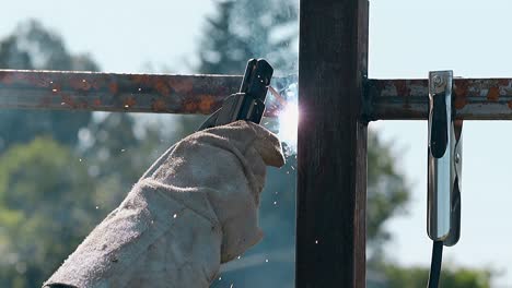 closeup-worker-in-gloves-welds-metal-carcass-of-fence