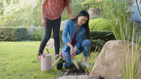 planting flowers in garden, asian mother and daughter enjoying gardening together