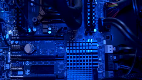 inside view of computer motherboard seeing heatsinks, capacitors, dimm and pci slot with rgb lighting, macro shot, dolly right