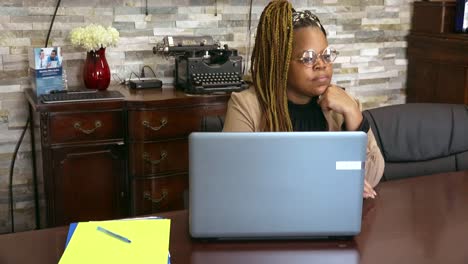 black employer taking a moment from working to gaze out of window on a sunny day