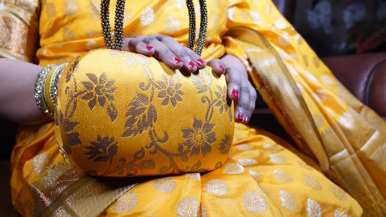 Donna che tiene una borsa floreale gialla con dettagli dorati