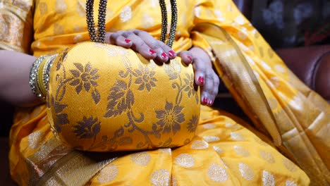 woman holding a yellow floral handbag with gold embellishments