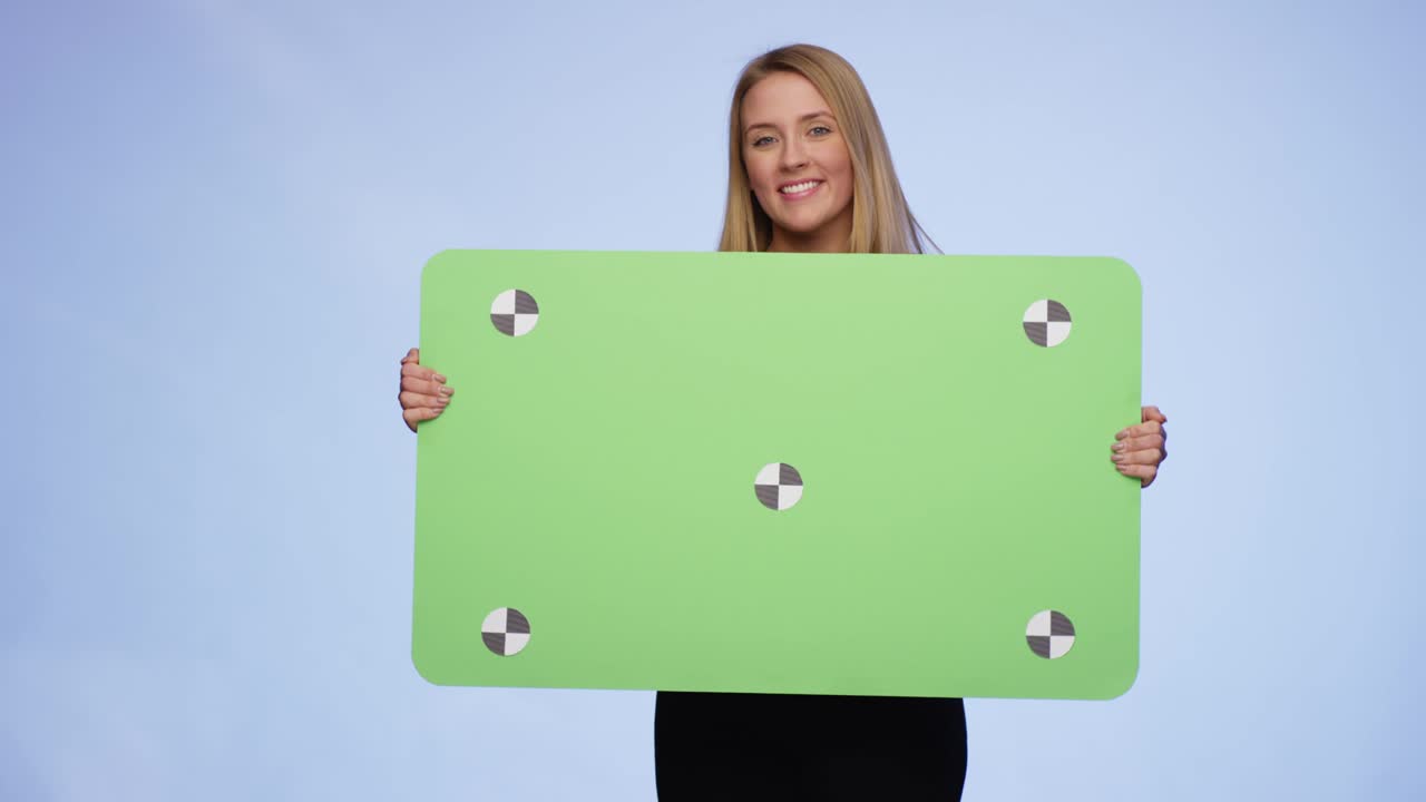 joven alegre entrando en la imagen sosteniendo una tarjeta de pantalla verde de gran tamaño y luego dejando la imagen