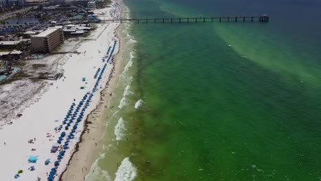 aerial view of fort walton beach destin florida with okaloosa island pier in background. tourist chairs umbrellas lined up on white sandy beach in destin okaloosa island florida