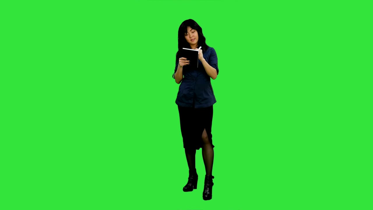 Giovane donna d'affari asiatica che prende appunti durante un'intervista su Green Screen, Chroma Key