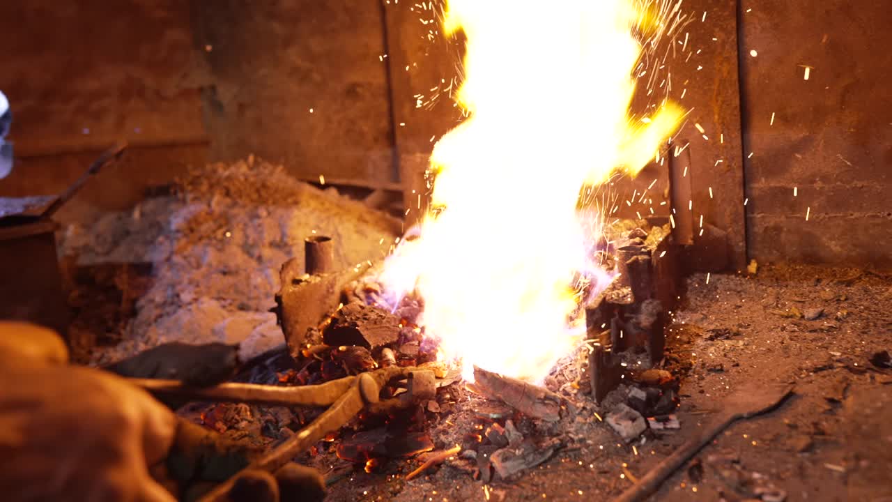 Craftsman heating iron in fire and preparing to create a knife