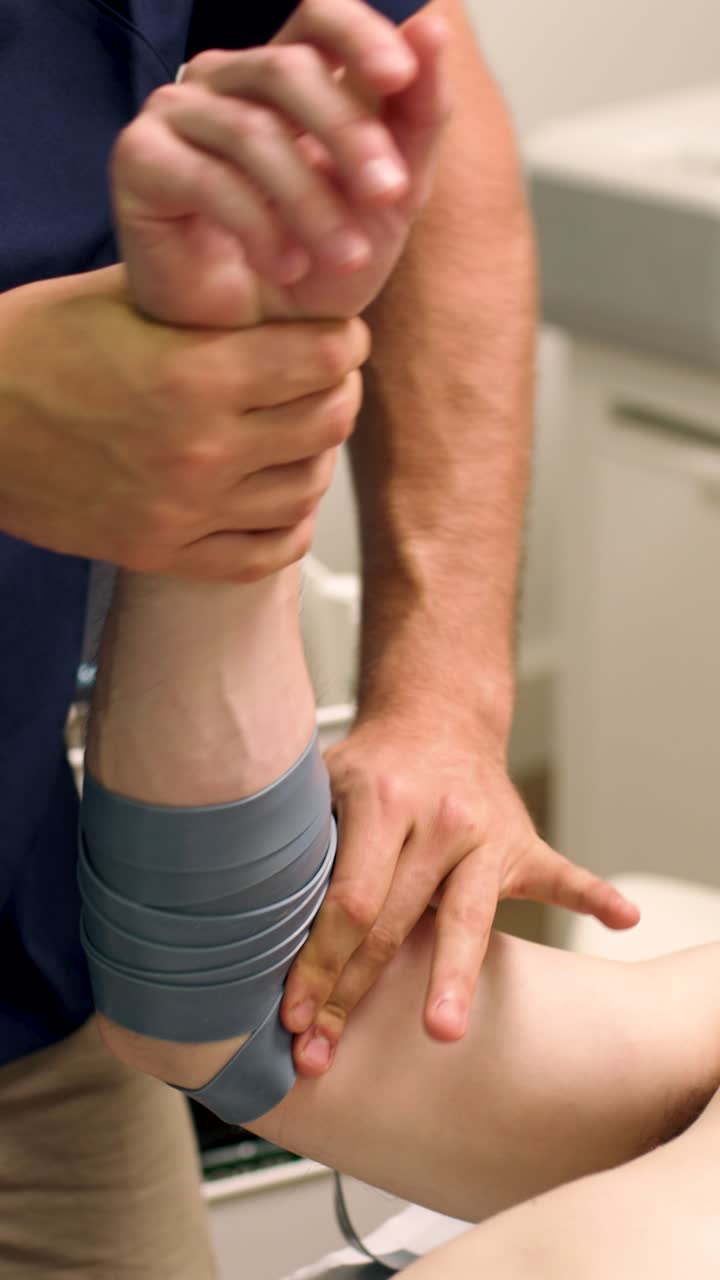 Therapist Applies Compression Band to Patient's Elbow During Rehabilitation