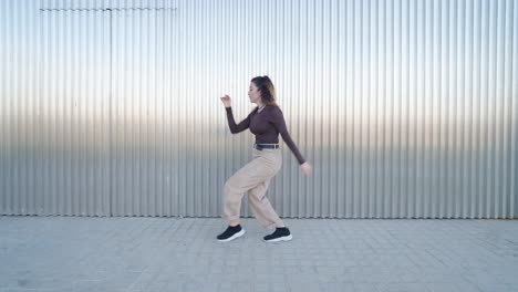 young woman dancing freestyle in front of metal wall