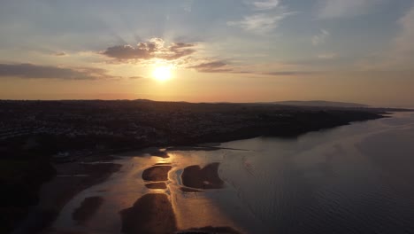 sunset rays beam fiery golden colours across relaxing beach ocean coastline aerial view rising high