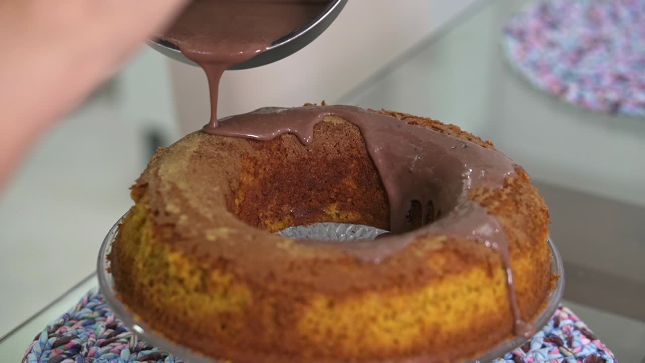 verter la salsa de chocolate que gotea en un simple pastel de zanahoria casero con una sartén negra preparar el postre antes de servir