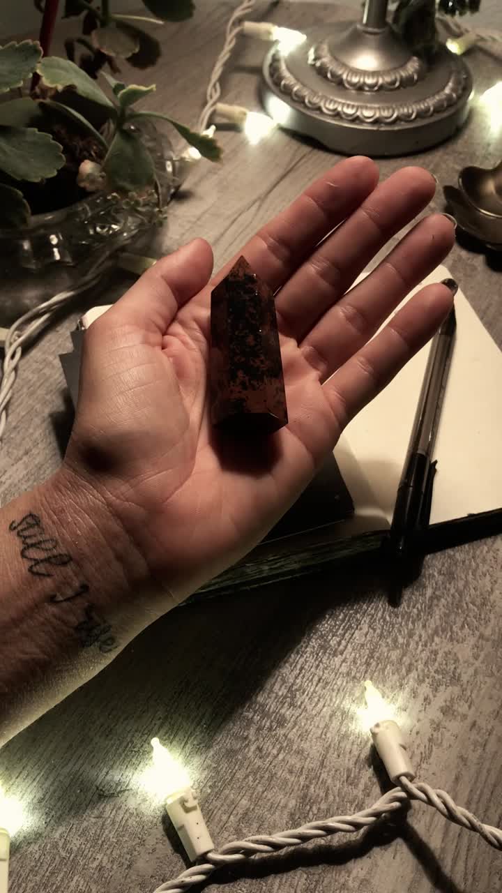 Hand with tattoo and crystal, journaling and Christmas lights