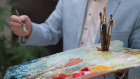 close-up of a painter's hand holding a brush and palette