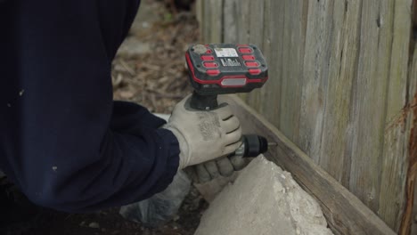 fixing an old wooden shed with cordless drill, hands in gloves