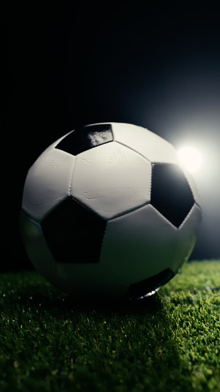 Karanlık bir stüdyoda çimin üzerinde dönen futbol topu.