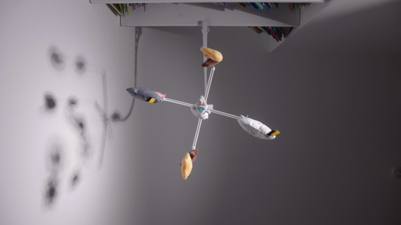 꿈꾸는 아기 침대 모바일 장난감이 벽에 그림자가 드리워진 아기 침대 위에 매달려 있습니다.