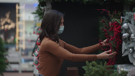 A-woman-in-a-protective-mask-in-a-jewelry-store-and-garlands-with-toys-for-Christmas-trees-and-at-home.-Christmas-garlands-and-decor