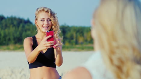 young woman photographed with a smartphone to his girlfriend on the beach showing gestures of approv