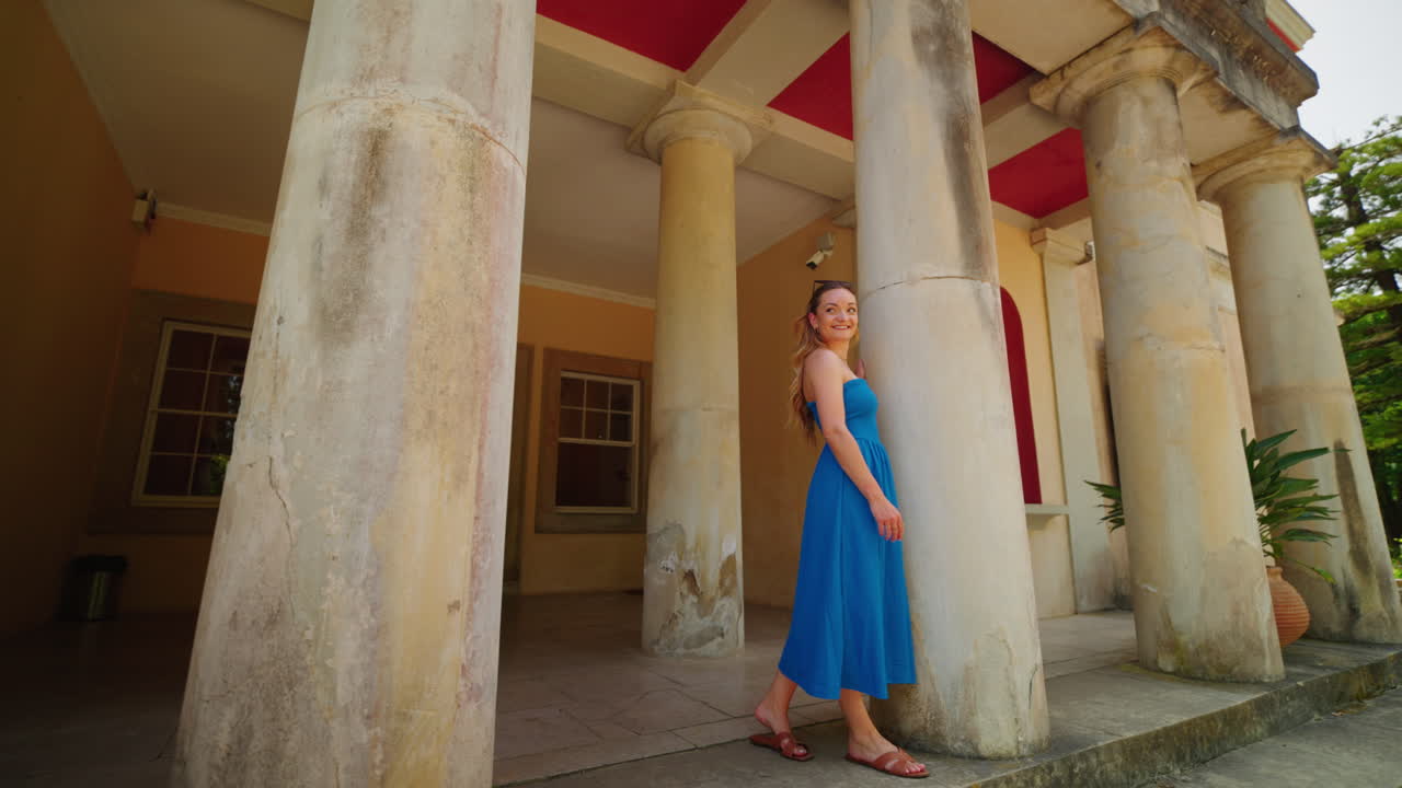 Woman in a blue dress exploring a historical building with grand columns