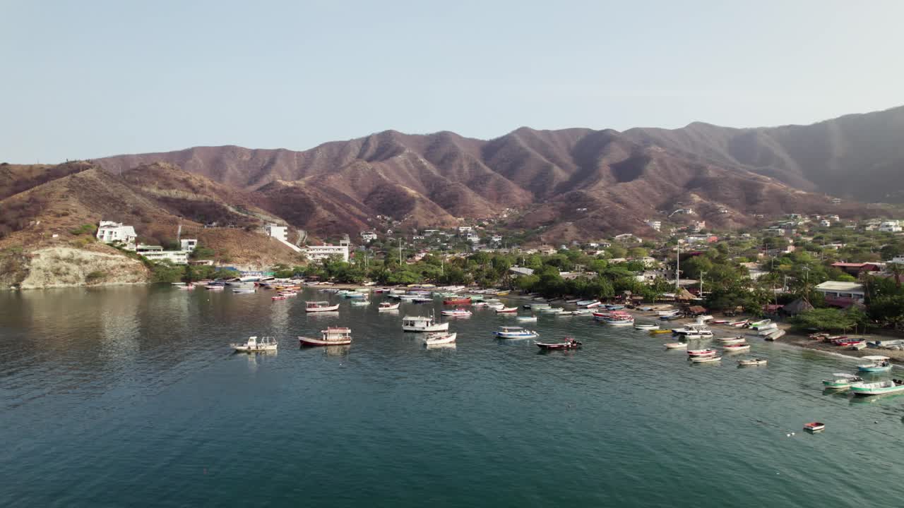 Ripresa aerea di una camionetta che attraversa la pittoresca baia di Taganga, in Colombia. Sono presenti pescherecci, un tranquillo lungomare e un colorato villaggio immerso tra le aride montagne tropicali dei Caraibi.