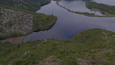 Black-camper-van-parked-at-Krka-National-Park-Croatia-near-a-lake-at-cloudy-day,-aerial