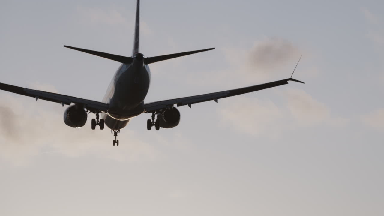 Avión volando en el cielo para aterrizar en el aeropuerto a cámara superlenta al atardecer
