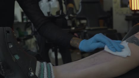 a woman in a tattoo shop sterilizes the leg of a client in preparation of inking a tattoo onto her skin