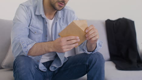 a handsome man is opening an envelope