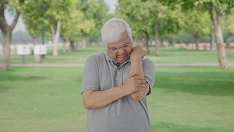 sick indian old man suffering from arthritis in park